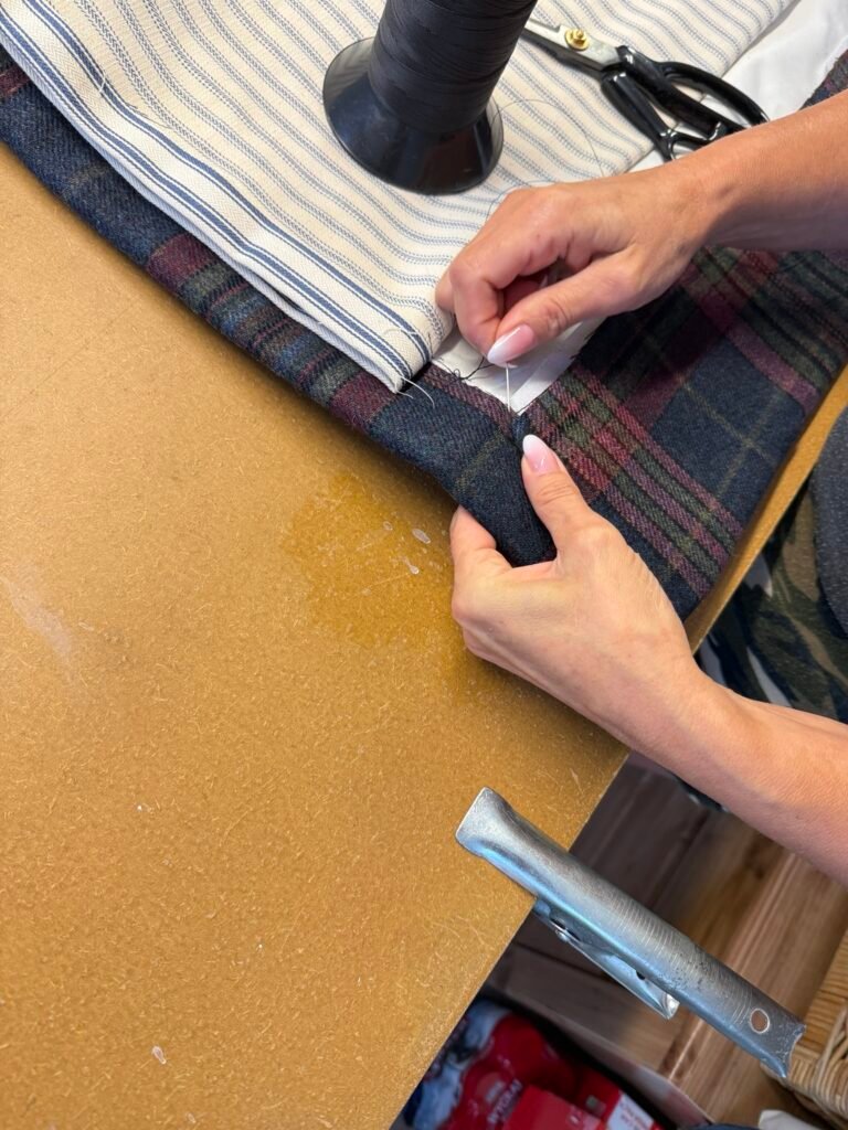 Hand stitching the corner of a bespoke tartan curtain
